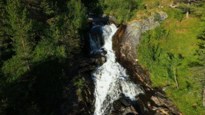 Waterfall rushing down the green summer forest